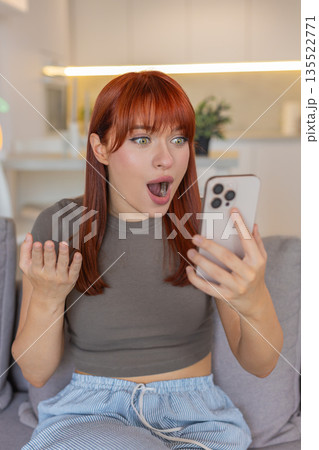 Young woman with smartphone whispers wow eyes wide open nods with delight positive approval reaction 135522771