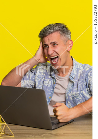 Adult man holding head in frustration while looking at laptop after mistake computer virus problem 135522793