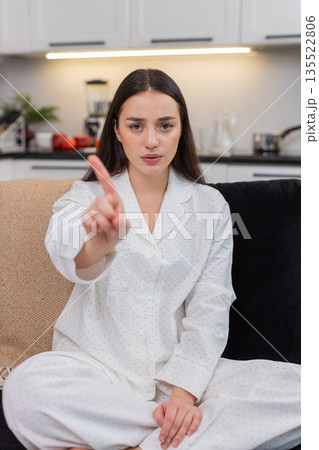 Young woman waves finger no sign disagrees refuses idea shows disapproval firm gesture stop warning 135522806