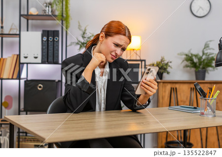 Young businesswoman despairs over big failure online game loss reading bad news sadly on smartphone Young businesswoman despairs over big failure online game loss reading bad news sadly on smartphone 135522847