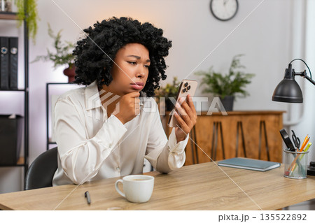 African American businesswoman upset sees bad news on smartphone after game loss reacts very shocked African American businesswoman upset sees bad news on smartphone after game loss reacts very shocked 135522892