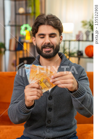 Indian man counts euro cash banknotes dreams of travel thinks where to spend money smiles very happy Indian man counts euro cash banknotes dreams of travel thinks where to spend money smiles very happy 135522908