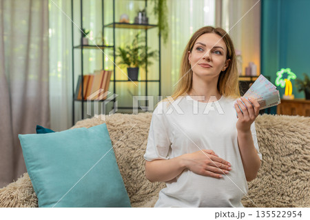Pregnant woman counts UAH Ukrainian hryvnia cash planning baby birth budget money preparation 135522954