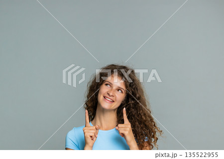 Woman smiling pointing upward presenting advertising promo logo product copy space cheerful gesture 135522955