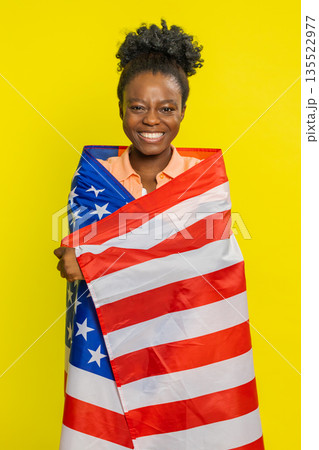 Black young woman waving and wrapping in American USA flag, celebrating, human rights and freedoms Black young woman waving and wrapping in American USA flag, celebrating, human rights and freedoms 135522977