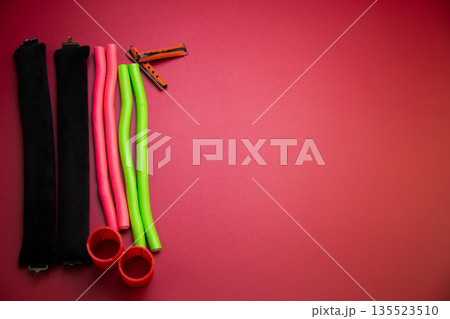 On the one hand, there are long bendable curlers for creating voluminous hairstyles, as well as small curlers for creating curls on a pink background with space for text. The concept of hairstyles On the one hand, there are long bendable curlers for creating voluminous hairstyles, as well as small curlers for creating curls on a pink background with space for text. The concept of hairstyles 135523510