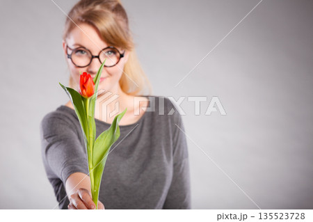 Blonde woman with single tulip. Blonde woman with single tulip. 135523728