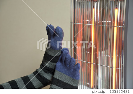 電気ストーブで暖をとる老人の足 135525481