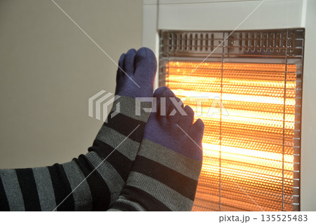 電気ストーブで暖をとる老人の足 135525483