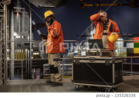 Concerned employee on offshore oil platform manages petroleum extraction using laptop, sweating and struggling to ensure safe oil extraction. Worried restless engineer in tension. 135526338