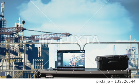 Laptop on drilling barge displaying predictive maintenance dashboard, monitoring machinery. Notebook on offshore platform deck digital analyzing performance metrics, zoom in shot 135526344
