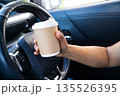 Asian lady holding hot coffee and drive in car, dangerous and risk an accident. 135526395