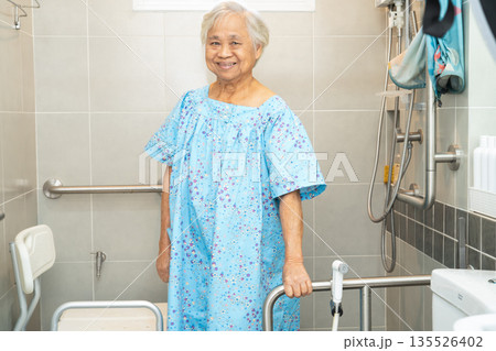 Asian elderly woman patient use toilet bathroom handle security in nursing hospital. 135526402
