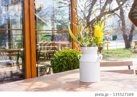 Spring bouquet of yellow tulips and white flowers in rustic metal vase on wooden table outdoors Spring bouquet of yellow tulips and white flowers in rustic metal vase on wooden table outdoors 135527169