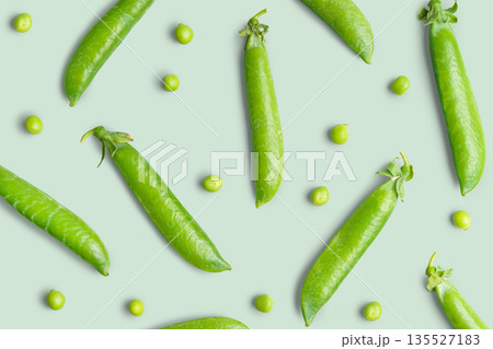 Fresh green pea pods arranged in natural organic pattern isolated on green background, close up Fresh green pea pods arranged in natural organic pattern isolated on green background, close up 135527183