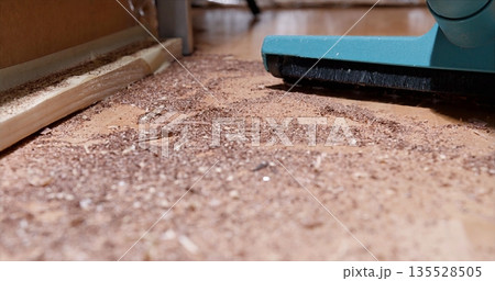Removing Fine Sawdust From Floor Surface, Closeup Of Vacuum Clearing Wooden Sawdust Along Baseboard Removing Fine Sawdust From Floor Surface, Closeup Of Vacuum Clearing Wooden Sawdust Along Baseboard 135528505