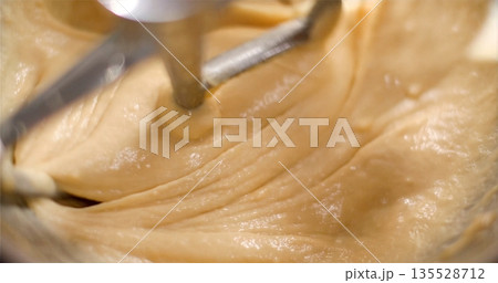 Vivid Swirl Of Batter Under Mixers, Effervescent Pale Caramel Batter With Tiny Bubbles And Motion Blur Vivid Swirl Of Batter Under Mixers, Effervescent Pale Caramel Batter With Tiny Bubbles And Motion Blur 135528712