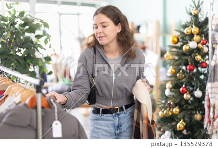Young woman choosing plaid jacket in clothing store Young woman choosing plaid jacket in clothing store 135529378