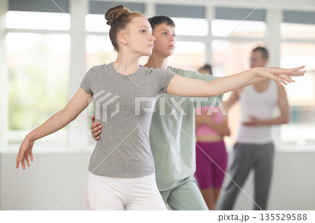 Teenage girl practicing ballet positions in pair with boy in dance studio 135529588