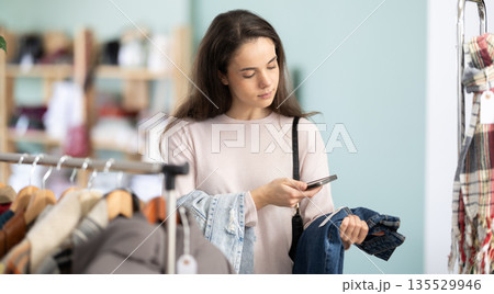 Young woman scanning barcode on jeans labels in store 135529946