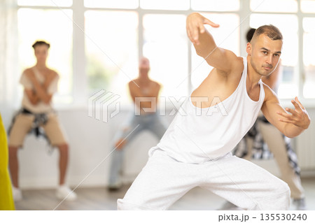 Young guy dancing hip-hop against background of group members 135530240