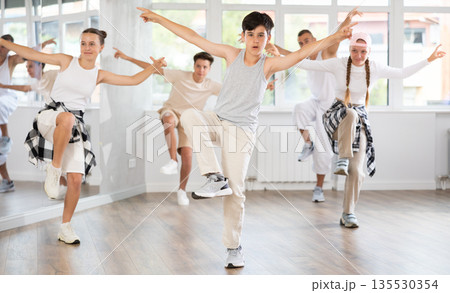 Teenage boy practicing hip hop reject step in training hall 135530354
