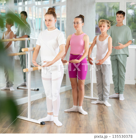 Teenage boys and girls practicing first position of ballet in dancehall 135530378