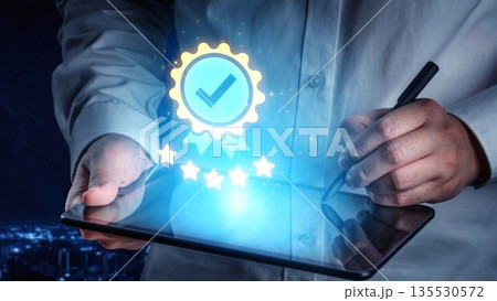 Hands holding a tablet with a glowing quality badge icon and five stars, representing achievement and digital certification in a modern business setting Gluon Hands holding a tablet with a glowing quality badge icon and five stars, representing achievement and digital certification in a modern business setting Gluon 135530572