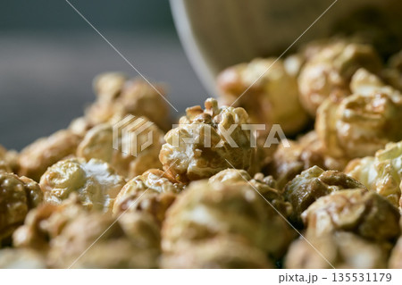 Close up of crunchy caramel glazed popcorn spilled on a dark rustic wooden background Close up of crunchy caramel glazed popcorn spilled on a dark rustic wooden background 135531179
