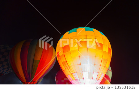 colorful hot air balloons glowing against dark night sky 135531618