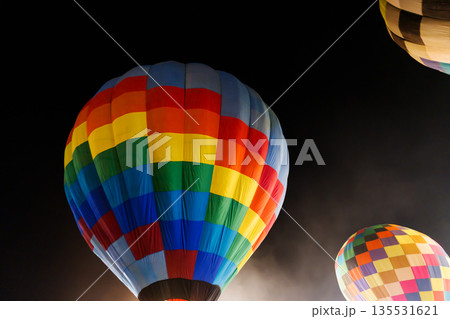 colorful hot air balloons glowing against dark night sky colorful hot air balloons glowing against dark night sky 135531621