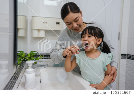 mother teaching girl child to brushing teeth in bathroom 135531667
