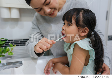 mother teaching girl child to brushing teeth in bathroom 135531670