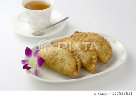 白背景にカレー揚げパイが3個とランの花が皿に盛りつけてティータイム 135532611