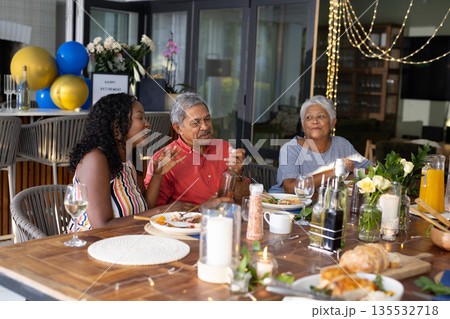 Family enjoying dinner together, sharing stories and laughter at festive table 135532718