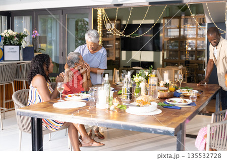 Sharing dinner, African American family laughing and creating joyful moments at home Sharing dinner, African American family laughing and creating joyful moments at home 135532728
