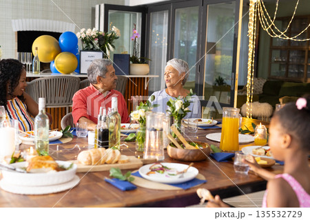 Family enjoying lively conversation and meal at home during festive celebration Family enjoying lively conversation and meal at home during festive celebration 135532729
