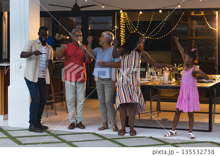 Family celebrating together outdoors, raising glasses and dancing joyfully at night Family celebrating together outdoors, raising glasses and dancing joyfully at night 135532738