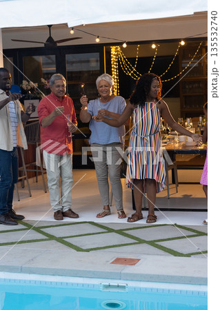 Celebrating by poolside, multigenerational family holding sparklers, smiling joyfully Celebrating by poolside, multigenerational family holding sparklers, smiling joyfully 135532740