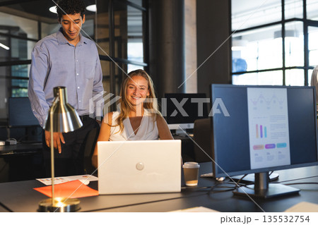Collaborating in modern office, colleagues discussing project details using laptop 135532754