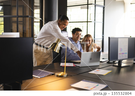 Business team collaborating on laptop in modern office, discussing project details Business team collaborating on laptop in modern office, discussing project details 135532804