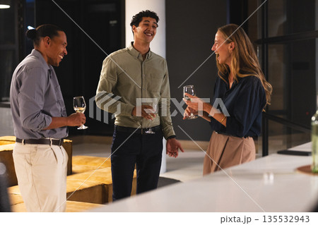Networking at office event, professionals conversing and holding wine glasses Networking at office event, professionals conversing and holding wine glasses 135532943