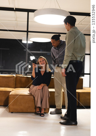 In modern office, woman showing smartphone while discussing ideas with professionals In modern office, woman showing smartphone while discussing ideas with professionals 135532946