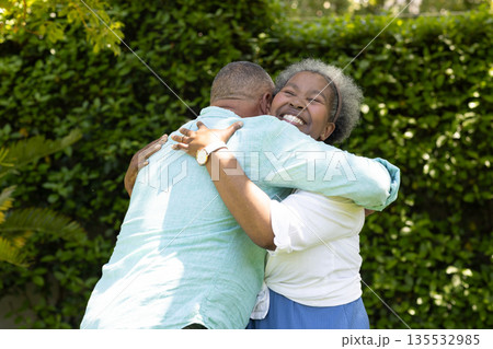 Senior couple embracing joyfully in garden, sharing warm and happy moment 135532985