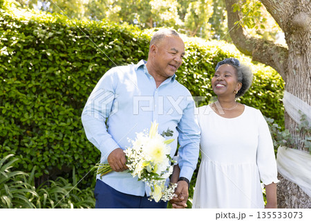 Senior couple walking in garden, holding bouquet, sharing joyful moment together Senior couple walking in garden, holding bouquet, sharing joyful moment together 135533073