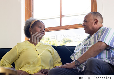 African American senior couple sitting on couch, having heartfelt conversation 135533124