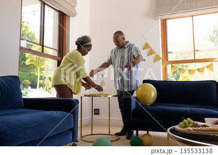 African American senior couple decorating living room with balloons for celebration African American senior couple decorating living room with balloons for celebration 135533138