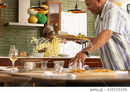 Preparing meal in modern kitchen, senior couple sharing wine and conversation Preparing meal in modern kitchen, senior couple sharing wine and conversation 135533159