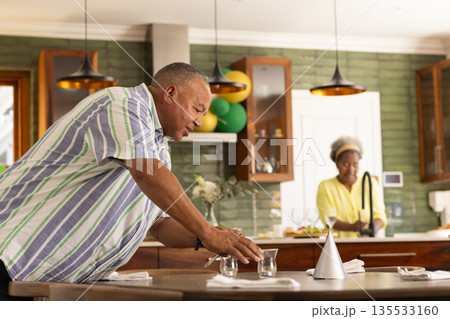 Senior couple preparing table for dinner at home, enjoying quality time together Senior couple preparing table for dinner at home, enjoying quality time together 135533160