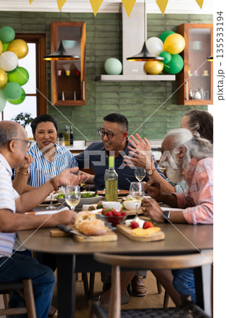 Senior friends enjoying lively conversation and meal together at home party Senior friends enjoying lively conversation and meal together at home party 135533194